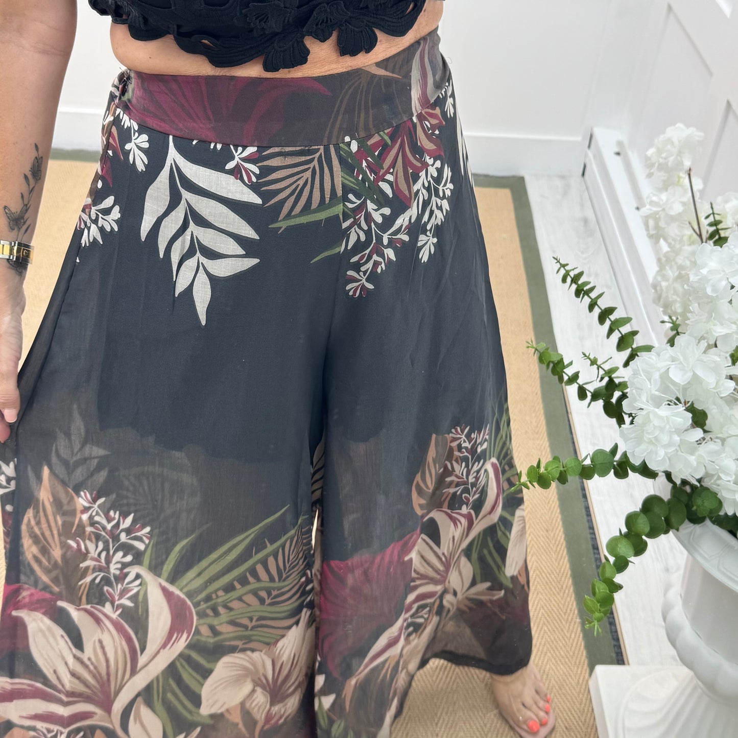 Lyra: Black tropical print wide leg sheer trousers. One size: 8-14