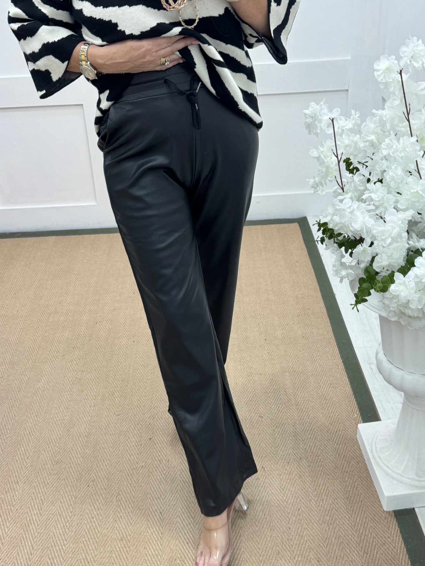 Geri: Black faux leather wide leg trousers.